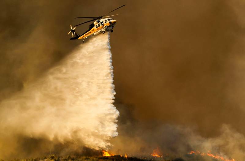 Helicopters were grounded briefly on Sunday after an unauthorized aerial drone was spotted in the skies above the wildfires. (Image: Associated Press)